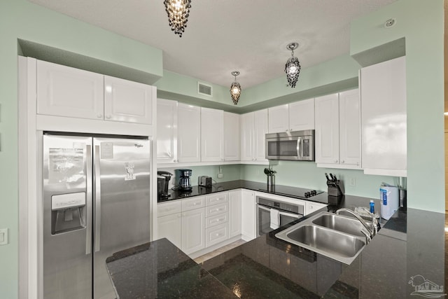 kitchen featuring pendant lighting, white cabinets, sink, appliances with stainless steel finishes, and kitchen peninsula