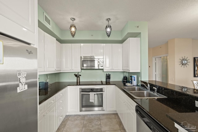 kitchen featuring white cabinetry, sink, stainless steel appliances, dark stone counters, and pendant lighting