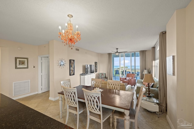 tiled dining space featuring ceiling fan with notable chandelier and a textured ceiling