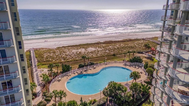 view of swimming pool featuring a water view and a beach view