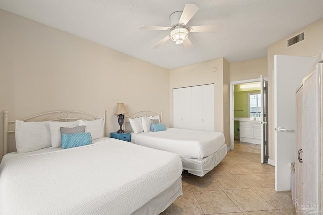 bedroom with ceiling fan, a closet, light tile patterned floors, and ensuite bath