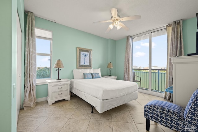 bedroom with ceiling fan, access to exterior, light tile patterned floors, and multiple windows