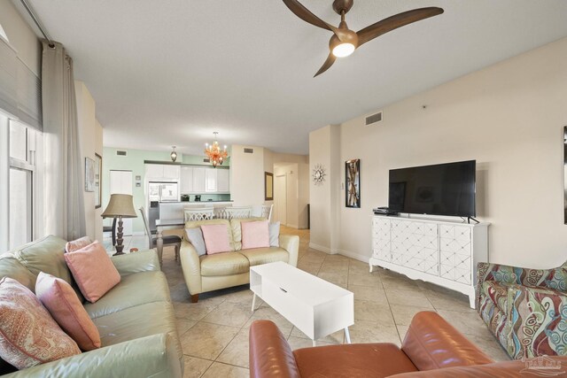 living room with light tile patterned floors, ceiling fan with notable chandelier, and plenty of natural light