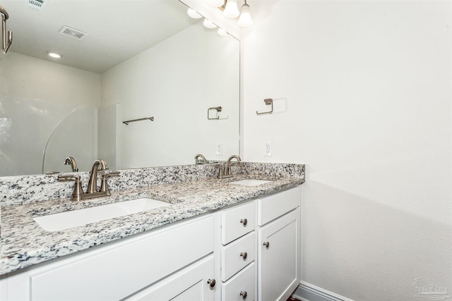 full bath with double vanity, baseboards, visible vents, and a sink