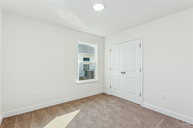 unfurnished bedroom with carpet, a closet, and baseboards