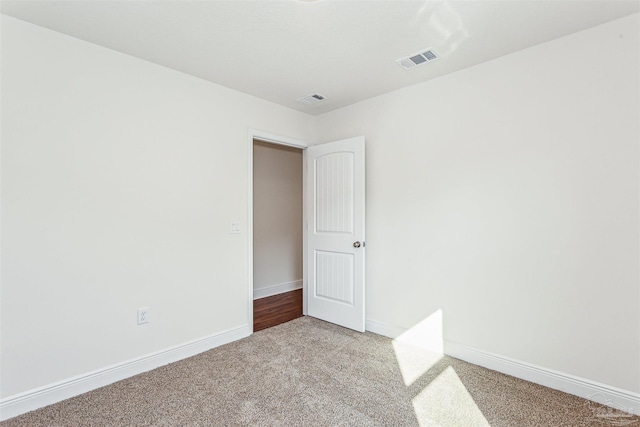 empty room featuring light colored carpet, visible vents, and baseboards