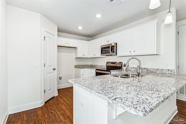 kitchen featuring visible vents, appliances with stainless steel finishes, a peninsula, light stone countertops, and a sink