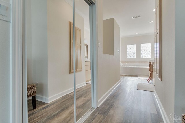 hallway with wood-type flooring and ornamental molding