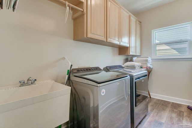 washroom with cabinets, sink, washing machine and dryer, and light hardwood / wood-style flooring