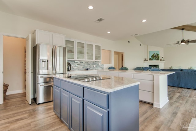 kitchen featuring appliances with stainless steel finishes, white cabinets, backsplash, a center island, and light wood-type flooring