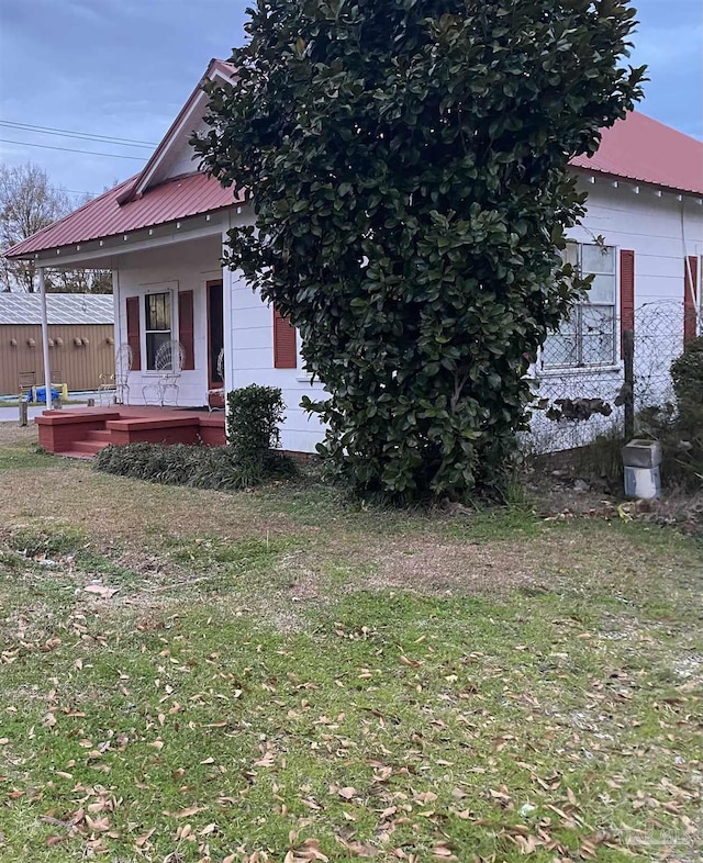 view of side of property with metal roof, a yard, and a porch