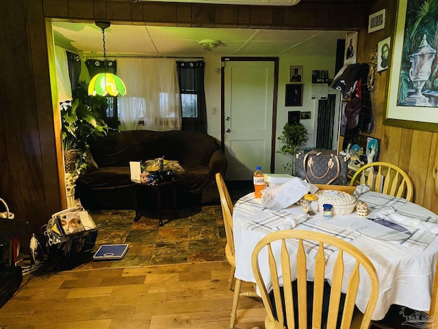 dining space featuring wood walls, wood finished floors, and visible vents