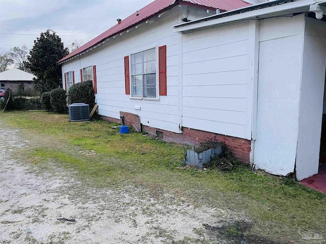 view of side of property with a yard, metal roof, and central air condition unit