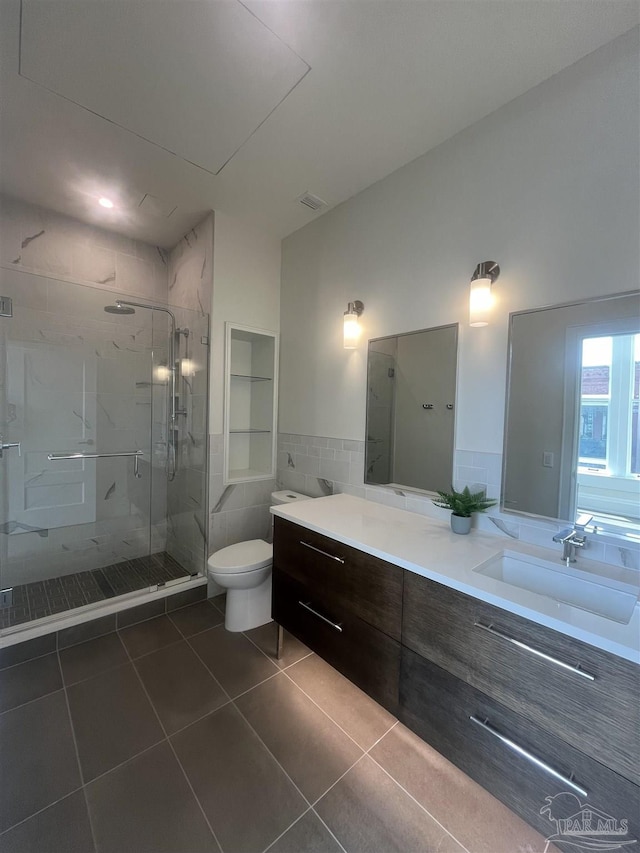 full bath with tile walls, toilet, a stall shower, vanity, and tile patterned floors