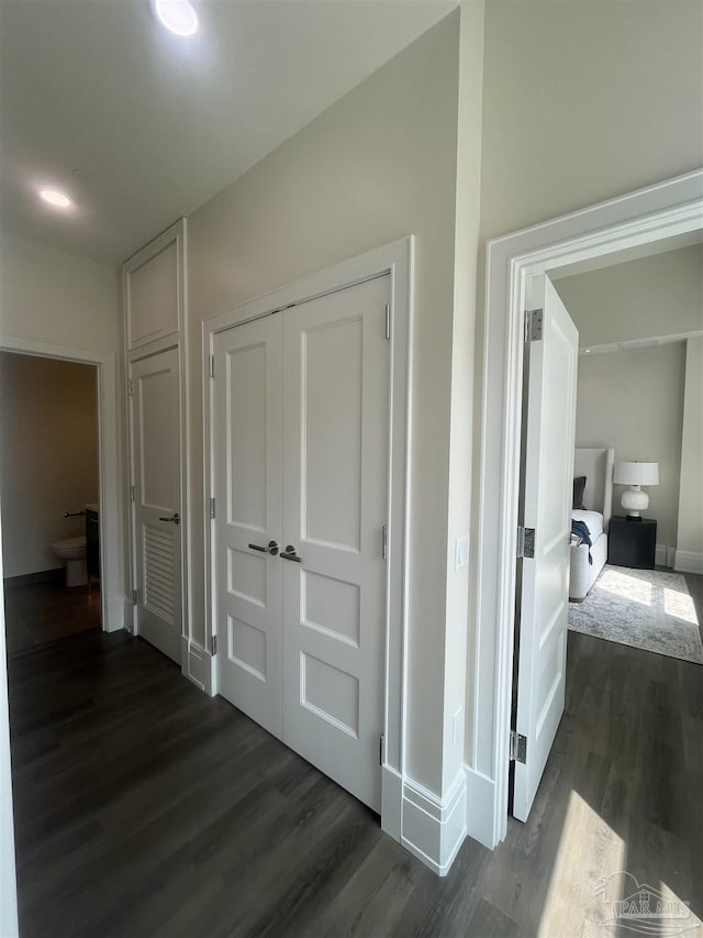 hallway featuring dark wood-style flooring and baseboards