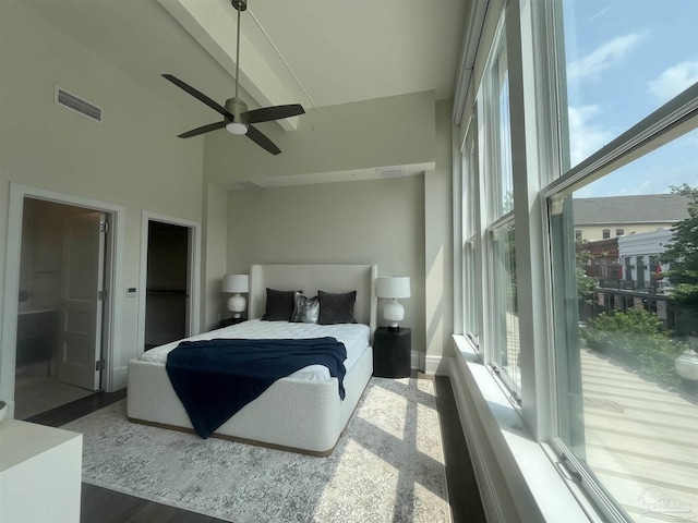 bedroom featuring a high ceiling, wood finished floors, visible vents, and a ceiling fan