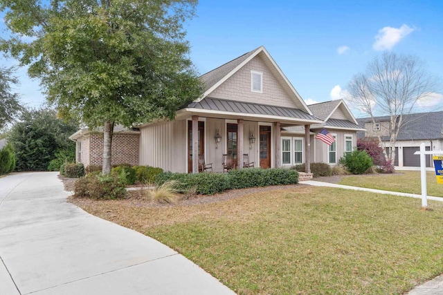 view of front facade featuring a standing seam roof, metal roof, a front lawn, and covered porch