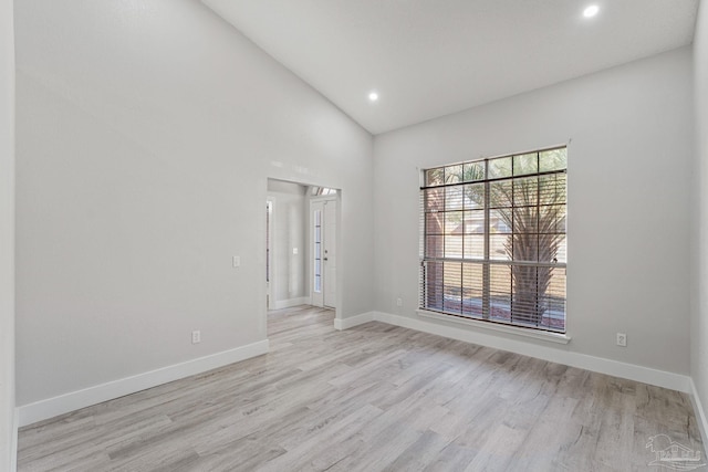 spare room featuring high vaulted ceiling and light hardwood / wood-style flooring