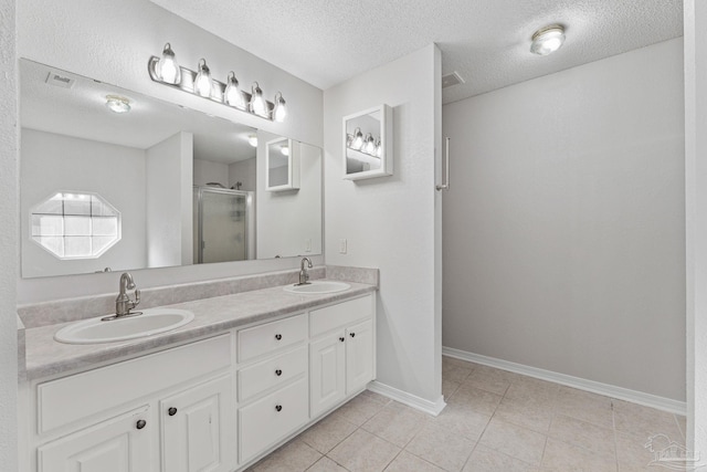 bathroom featuring tile patterned floors, a shower with door, vanity, and a textured ceiling