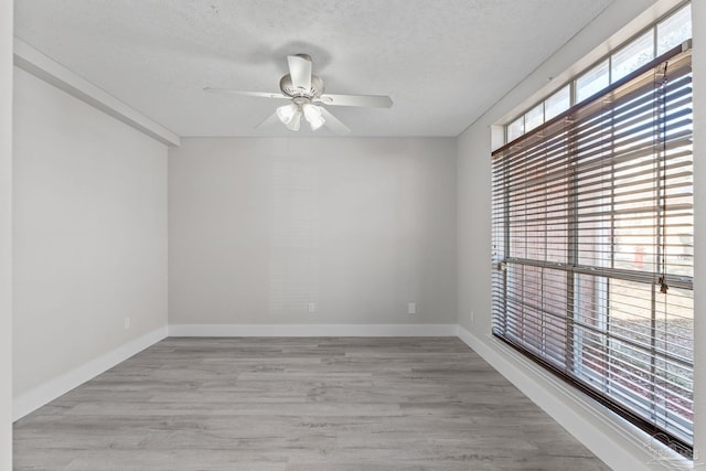 empty room featuring ceiling fan, light wood-type flooring, and a textured ceiling