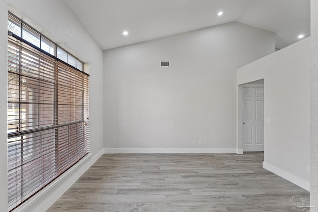 empty room with high vaulted ceiling and light wood-type flooring