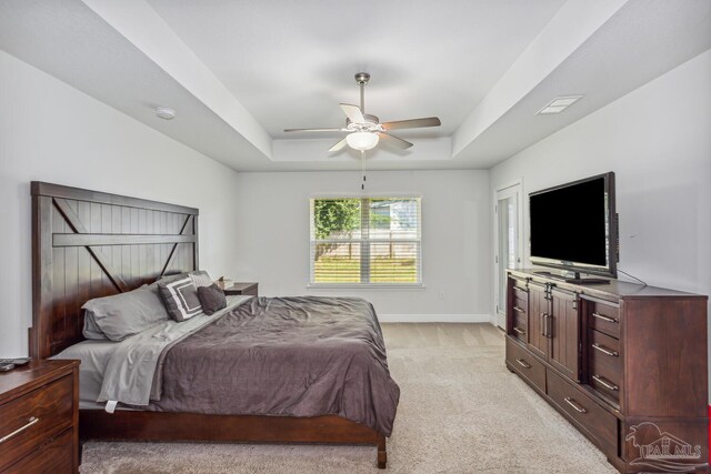 carpeted bedroom featuring a tray ceiling and ceiling fan