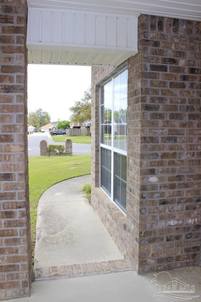 view of exterior entry featuring brick siding and a yard