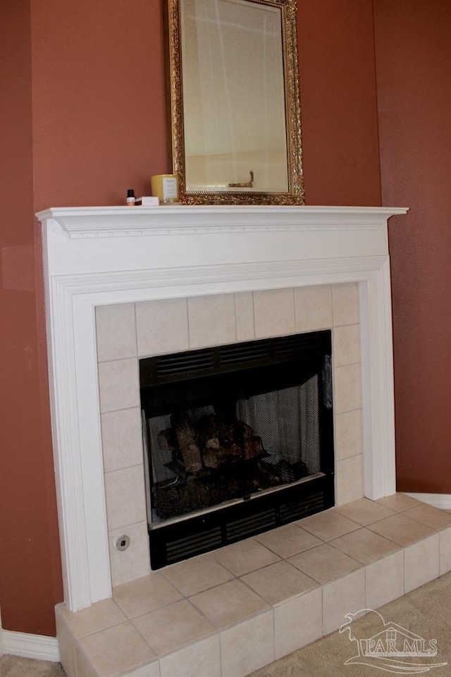details with a tiled fireplace and baseboards