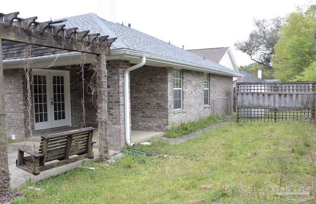 view of home's exterior with fence, french doors, and brick siding