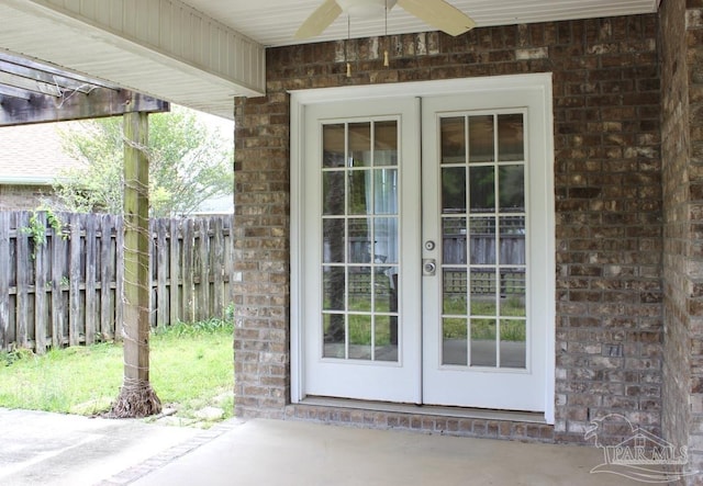 doorway to property featuring french doors, fence, brick siding, ceiling fan, and a patio