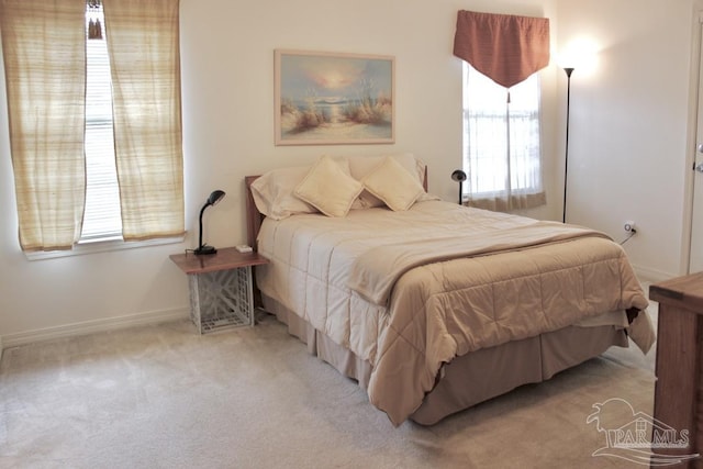 carpeted bedroom featuring baseboards and multiple windows