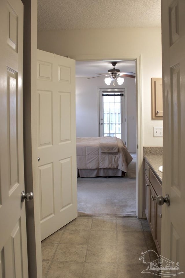 bathroom with tile patterned floors, a ceiling fan, vanity, a textured ceiling, and ensuite bathroom