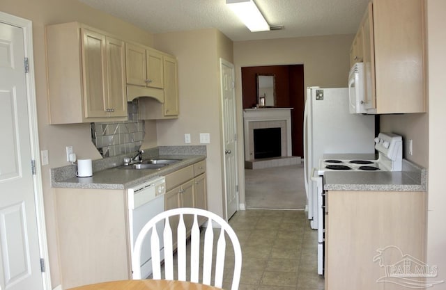 kitchen with a fireplace with raised hearth, light countertops, a sink, white appliances, and a textured ceiling