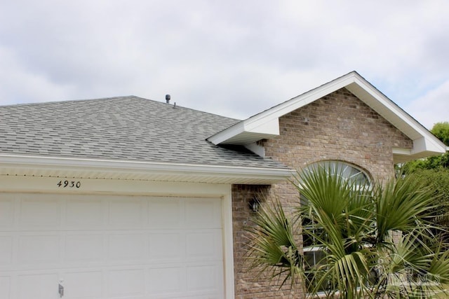 view of front of property with brick siding, a shingled roof, and a garage