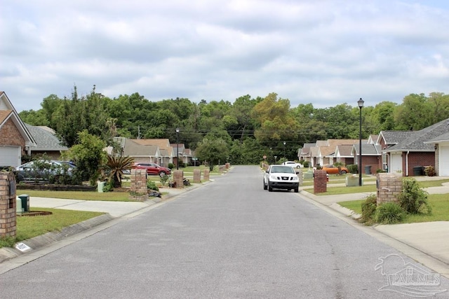 view of road featuring street lights, curbs, and a residential view