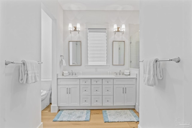 bathroom with walk in shower, vanity, wood-type flooring, and toilet