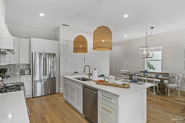 kitchen featuring white cabinetry, sink, stainless steel appliances, an island with sink, and light wood-type flooring