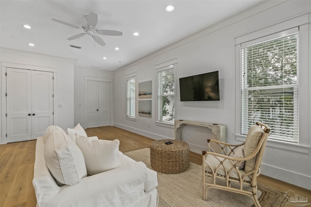 living room with light hardwood / wood-style floors, ceiling fan, and ornamental molding