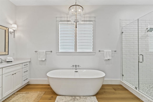 bathroom featuring hardwood / wood-style flooring, vanity, separate shower and tub, and an inviting chandelier