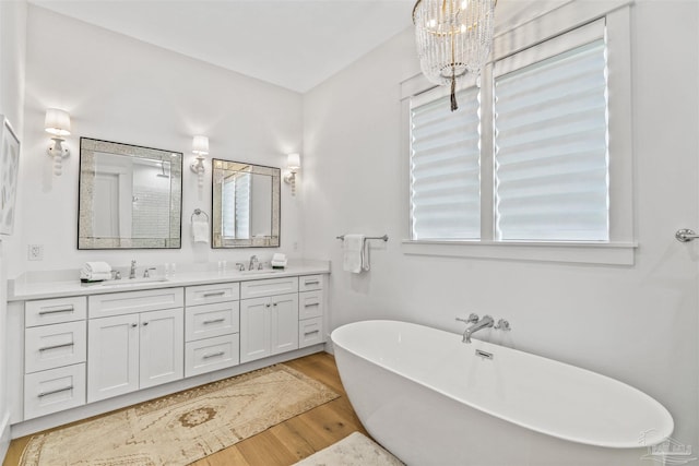 bathroom with vanity, a bath, a notable chandelier, and hardwood / wood-style flooring