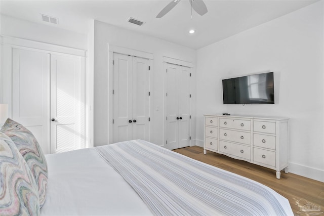 bedroom with ceiling fan, wood-type flooring, and two closets