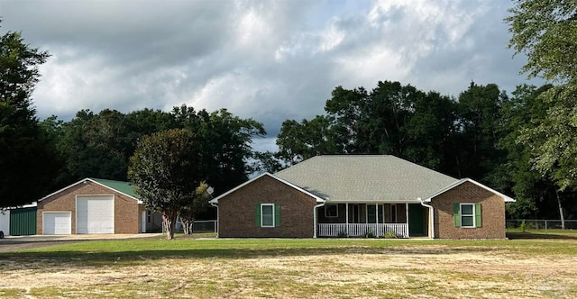 single story home featuring covered porch, a garage, an outdoor structure, and a front yard