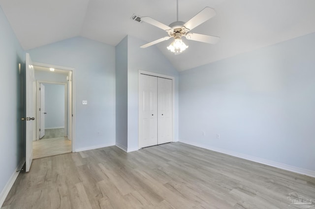 unfurnished bedroom with light wood-type flooring, a closet, vaulted ceiling, and ceiling fan