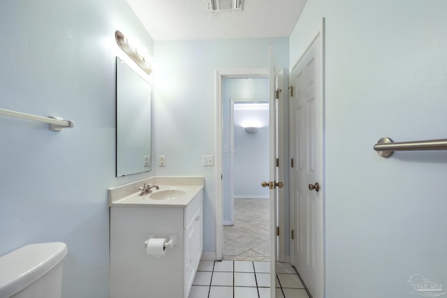 bathroom featuring tile patterned flooring, vanity, a textured ceiling, and toilet