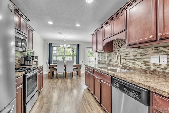 3818 Weatherstone Cir, Pensacola, FL 32507 - kitchen with appliances with stainless steel finishes, light wood-style floors, decorative backsplash, a chandelier, and a textured ceiling