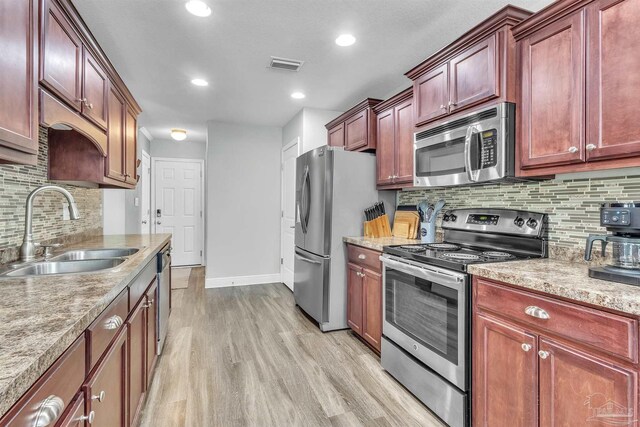 3818 Weatherstone Cir, Pensacola, FL 32507 - kitchen with appliances with stainless steel finishes, light wood-style flooring, tasteful backsplash, reddish brown cabinets, and recessed lighting
