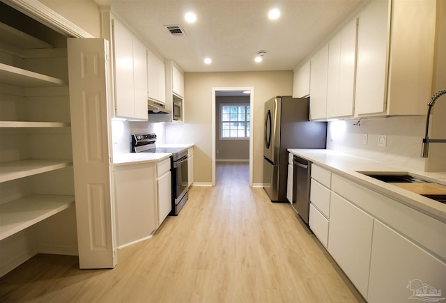 kitchen featuring stainless steel appliances, white cabinets, light hardwood / wood-style floors, and sink