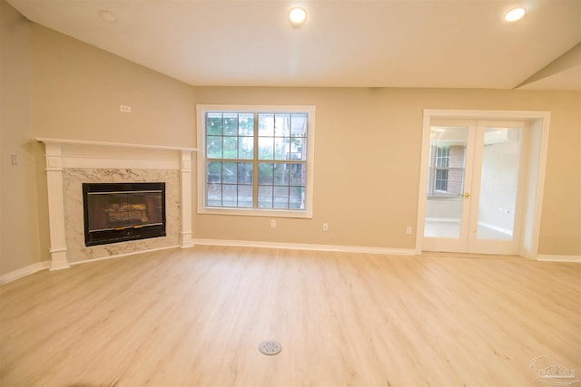 unfurnished living room featuring light hardwood / wood-style floors, vaulted ceiling, and a premium fireplace