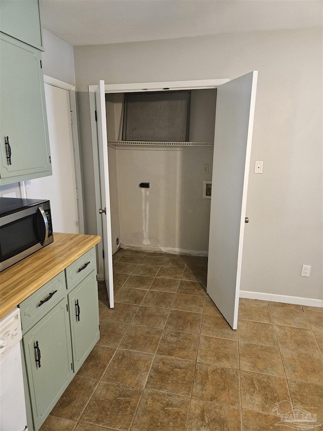 laundry area featuring dark tile patterned floors and baseboards