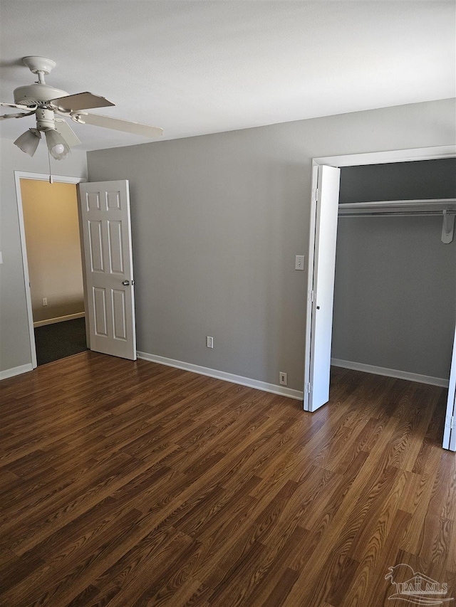 unfurnished bedroom with dark wood finished floors, a closet, and baseboards